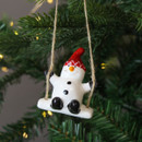 A view of a ceramic snowman on a swing hanging decoration hanging on a Christmas tree