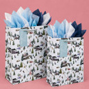 Two winter ski scene Christmas gift bags in different sizes with silver rope handles, blue "Merry Christmas" gift tags and blue, white and navy tissue paper.