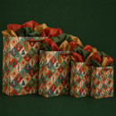 Four Christmas gift bags in different sizes with red rope handles, festive patchwork designs and red, green and gold tissue paper.