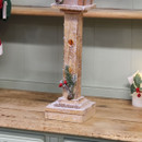 Snow-covered wooden Christmas street lamp with festive greenery and red berries.