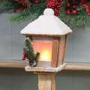Close-up of warm white LED lantern with snowy roof and pinecone details.
