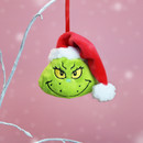 Grinch head Christmas tree decoration wearing a red Santa hat, hanging from a decorative branch