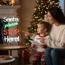 Mother and child sitting by a Christmas tree, smiling and pointing at a neon sign that reads Santa please STOP Here!. Mother and child sitting by a Christmas tree, smiling and pointing at a neon sign that reads Santa please STOP Here!.