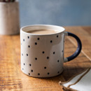 A white mug with Navy spots and handle on a table.