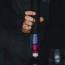 Someone using the electric corkscrew to unscrew the cork in a wine bottle.