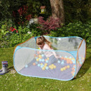 A ball pit in the garden, filled with colourful balls with a child sat inside.