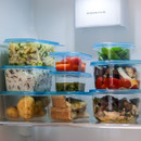 The storage containers stacked in the fridge with different foods inside.