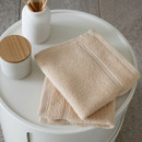 A view of a pack of 2 natural Catherine Lansfield Zero Twist Cotton Face Towels on a side table