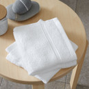 A view of a pack of 2 white Catherine Lansfield Zero Twist Cotton Face Towels on a side table