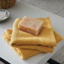 A view of a pack of 2 yellow Catherine Lansfield Zero Twist Cotton Face Towels on a side table