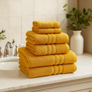 A view of all the Catherine Lansfield Zero Twist Cotton Towels in yellow stacked on a counter top