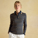 A woman models a navy blue and tan striped long-sleeve polo shirt, standing against a soft beige background.