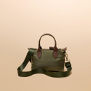Khaki green handbag with brown leather accents and a detachable strap, set against a soft beige background.