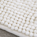 A close up view of a cream Catherine Lansfield Bobble Bath Mat on a tiled floor