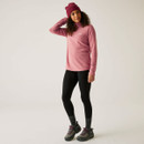 A full length view of a woman wearing a dusty pink quarter zip fleece with leggings and walking boots.