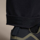 Reinforced hem of men’s black outdoor trousers, designed for durability with hiking boots.