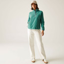 A full length view of a woman wearing a green half zip fleece with white trousers and trainers.