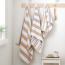 A view of natural striped Bianca Fine Linens hand towel, bath towel, bath sheet hung on hooks A view of natural striped Bianca Fine Linens hand towel, bath towel, bath sheet hung on hooks