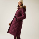 A side view of a woman wearing a quilted, fig coloured jacket with a faux fur hood.