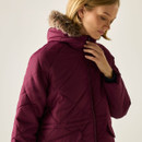 Close-up of the woman looking down while wearing the quilted coat, emphasising the hood’s faux-fur trim and the diagonal stitching detail.