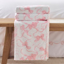 A view of a pink bow Catherine Lansfield blanket on a wooden bench