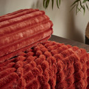 A close up view of a burnt orange Catherine Lansfield ribbed blanket