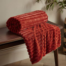 A view of a burnt orange Catherine Lansfield ribbed blanket on a wooden bench