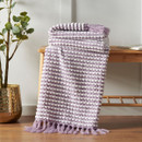 A view of a lilac Catherine Lansfield stab stitch blanket on a wooden stool