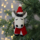 A felt cow decoration hanging from the tree.