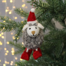 A felt sheep decoration from the front with red skis and a red hat.