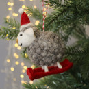 A felt sheep from the side with red skis and a red hat.