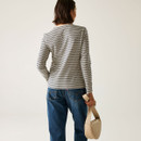 The back of a woman wearing a long sleeved, vanilla and navy coloured, striped top.