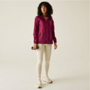 A full length view of a woman wearing a pink waterproof jacket with white leggings and trainers.
