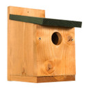 A wooden birdhouse with a rustic finish and visible wood grain. It features a small round entrance and a dark green slanted roof, evoking a cosy, natural feel.