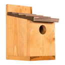 Wooden birdhouse with a pitched roof and circular entrance. The natural wood texture suggests simplicity and a welcoming rustic charm.