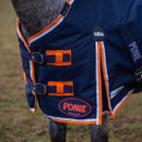 ose-up of the rug’s front fastening and shoulder area, highlighting the metal buckles, orange strap loops, “100G” label, and navy fabric with orange/white edging.