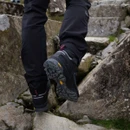 Rear view of black hiking boots climbing rocky steps, showing deep tread soles and supportive padded ankle collars.