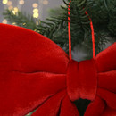 Close-up of a plush red bow hanging on a Christmas tree branch, with warm white lights softly glowing in the blurred background, conveying festive cheer.