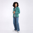 A full length view of a woman wearing a light green full zip fleece with jeans and trainers.