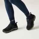 Black walking shoes with teal laces and rugged grip soles, worn with navy hiking socks and leggings while walking.
