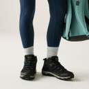 Black mid-height walking boots worn with outdoor clothing, showing the supportive ankle design and lace-up fastening.