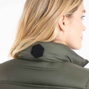 Close-up rear view of a woman wearing an olive green quilted gilet with a black rubber hexagonal "Weird Fish" logo patch on the back of the collar.