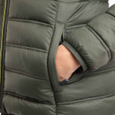 Close-up of a woman’s hand tucked into the side pocket of a deep lichen green padded jacket.