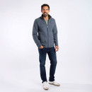 A full length view of a man wearing a navy fleece with jeans and trainers.