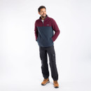 A full length view of a man wearing a navy and aubergine coloured quarter zip fleece with trousers and boots.