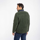 A man is standing with his back to the camera, wearing a green fleece jacket and jeans. The background is plain white, giving a casual tone.