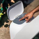 Close-up of a hand operating the MSpa Tribeca Hot Tub’s built-in control box, with the lid open and touchscreen interface clearly visible in an outdoor setting.