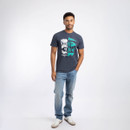 A full length view of a man wearing a navy t-shirt with jeans and trainers.