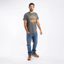 A full length view of a man wearing a grey coloured t-shirt with jeans and walking boots.