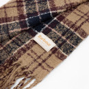 A soft woven scarf with a beige, navy, and burgundy checkered pattern, featuring a fringe detail. A "Barbour" label is attached, suggesting classic style.